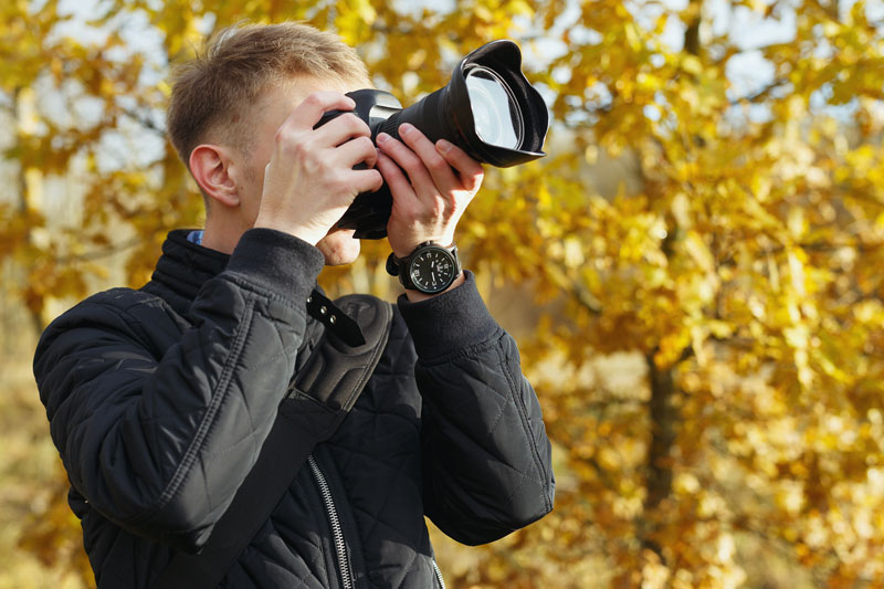 man looking through camera wearing a light jacket