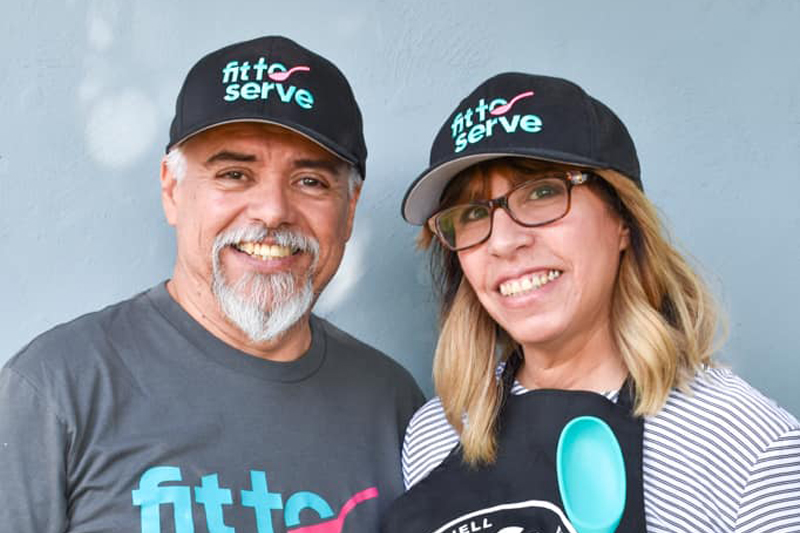 Hilda and partner wearing fit to serve shirts and hats