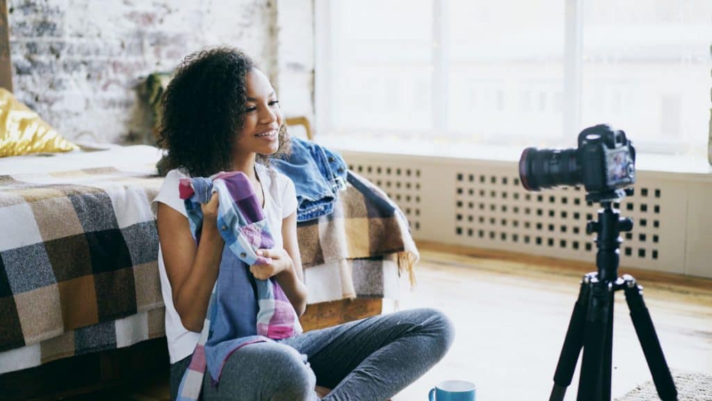 young female fashion blogger showing off a colorful plaid shirt to a video camera