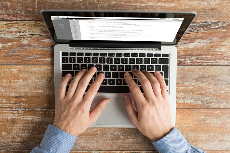 overhead image of hands typing on a laptop