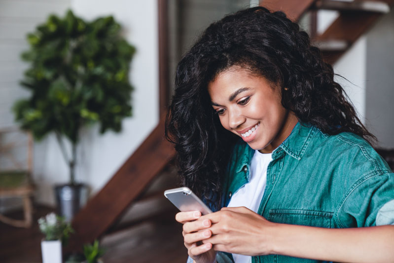 person sitting on couch smiling at phone