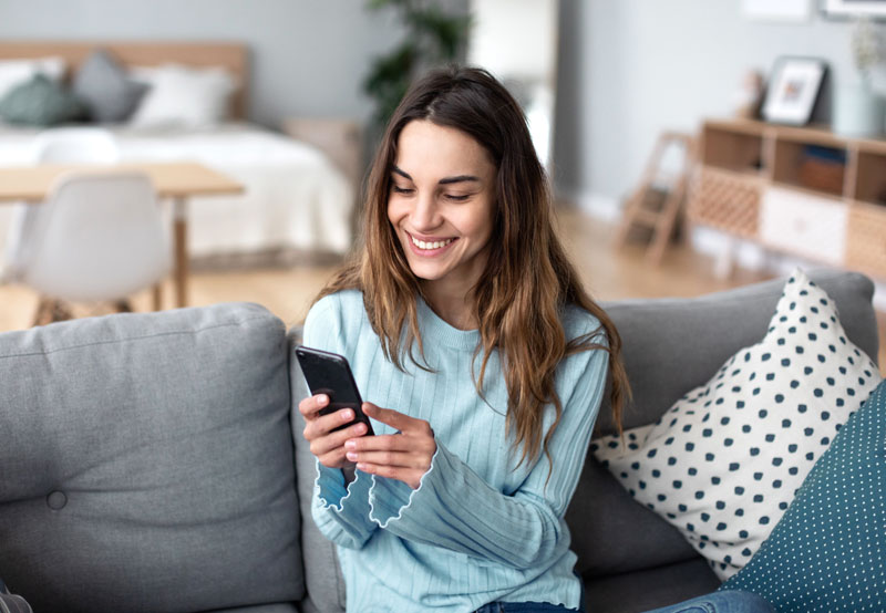 woman sitting on couch using phone