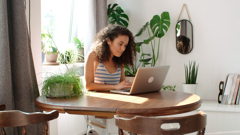 woman using computer surrounded by plants