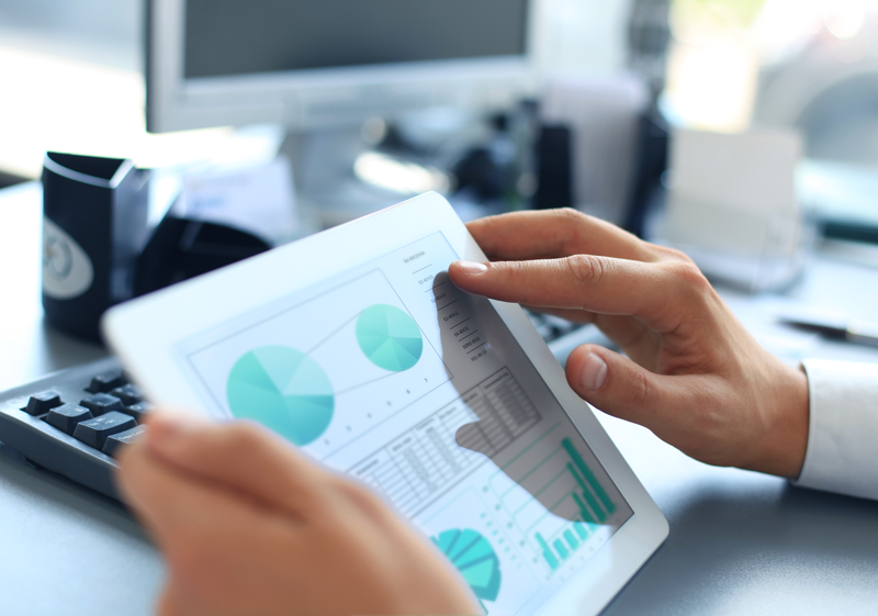 business person with hands on ipad displaying pie charts and graphs
